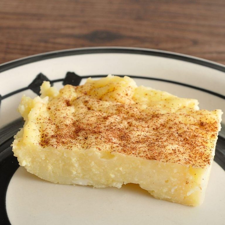 slice of milk tart on a white plate with black rings with a wooden background